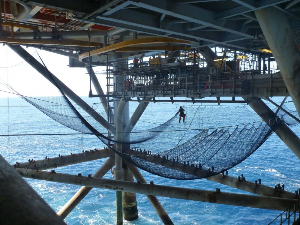 Team member in safety harness above netting